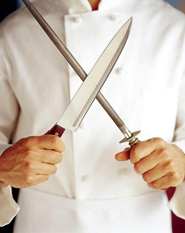 A chef is pictured holding a knife and a honing rod
