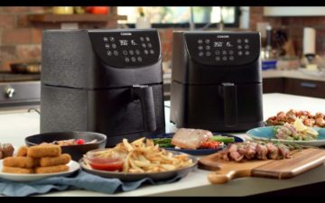 Two air fryers on a countertop with air-fried food in front