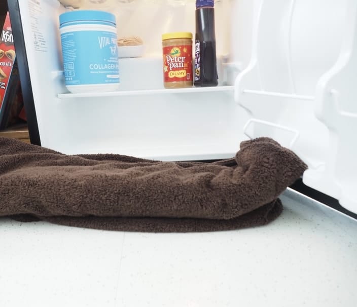 Putting a towel under a mini fridge to defrost