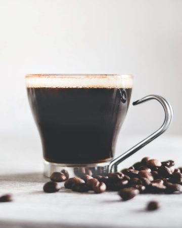 Cup of coffee and dark roast coffee beans