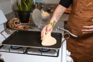 chef making tortillas on a stove top griddle. 